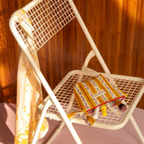 Petite trousse beauté Flora Passion sur une chaise blanche, foulard fleuri sur le dossier