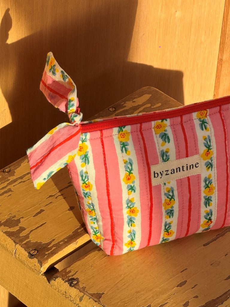 Gros plan sur la trousse beauté Flora Rose à nœud et son étiquette byzantine