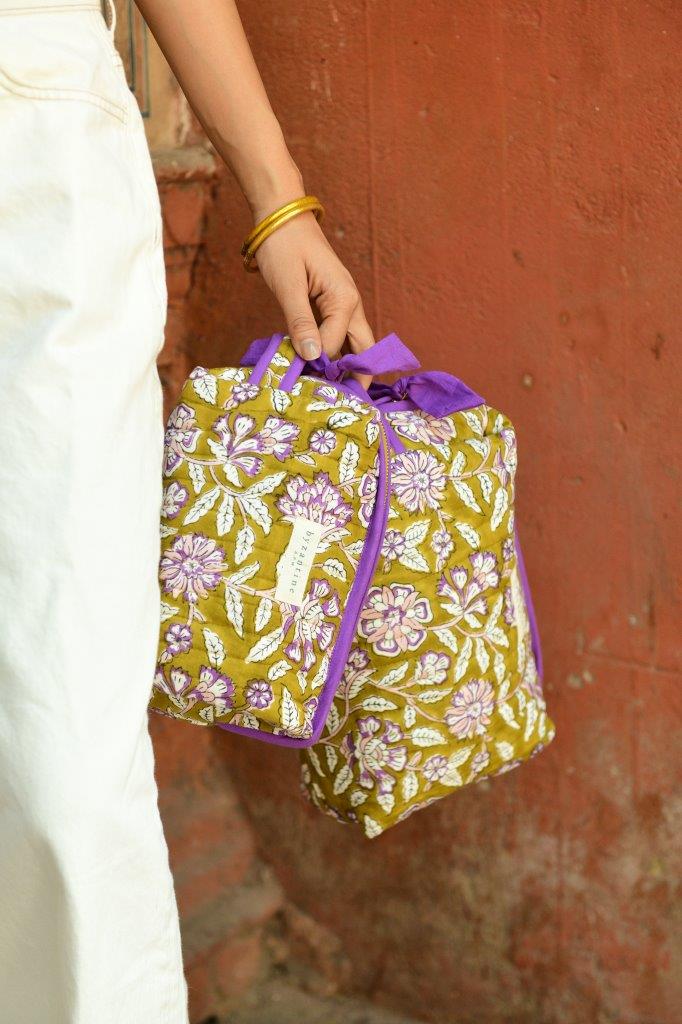 Petite trousse de toilette Carthage Kaki tenue à la main, pantalon écru