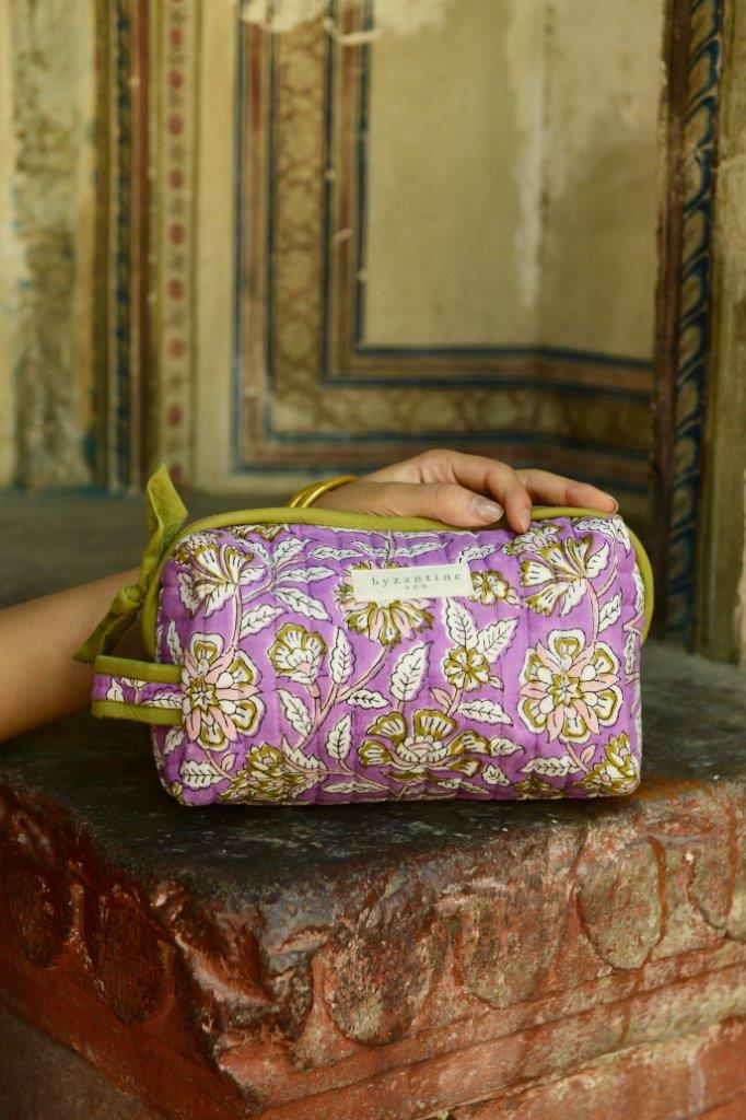 Petite trousse de toilette Carthage Lilas, fleurs écrues sur fond lilas, sur un muret