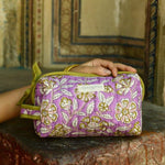 Petite trousse de toilette Carthage Lilas, fleurs écrues sur fond lilas, sur un muret