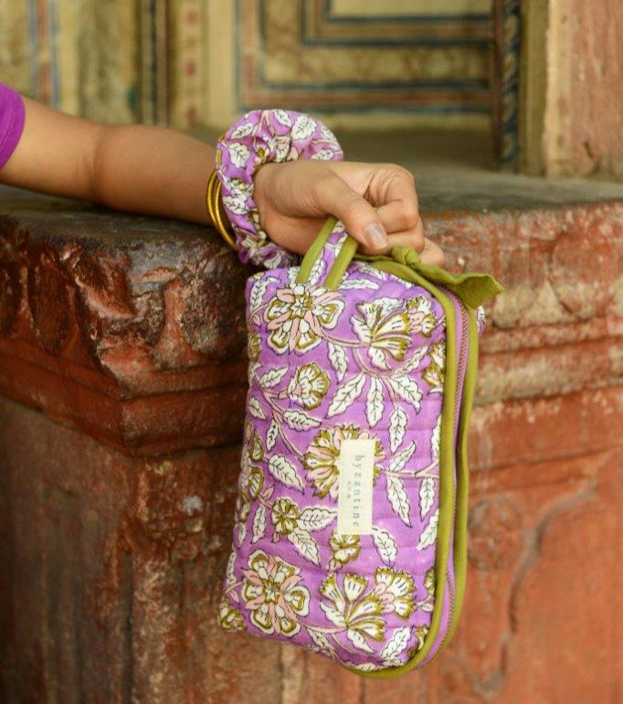 Petite trousse de toilette Carthage Lilas tenue à la main avec un chouchou assorti