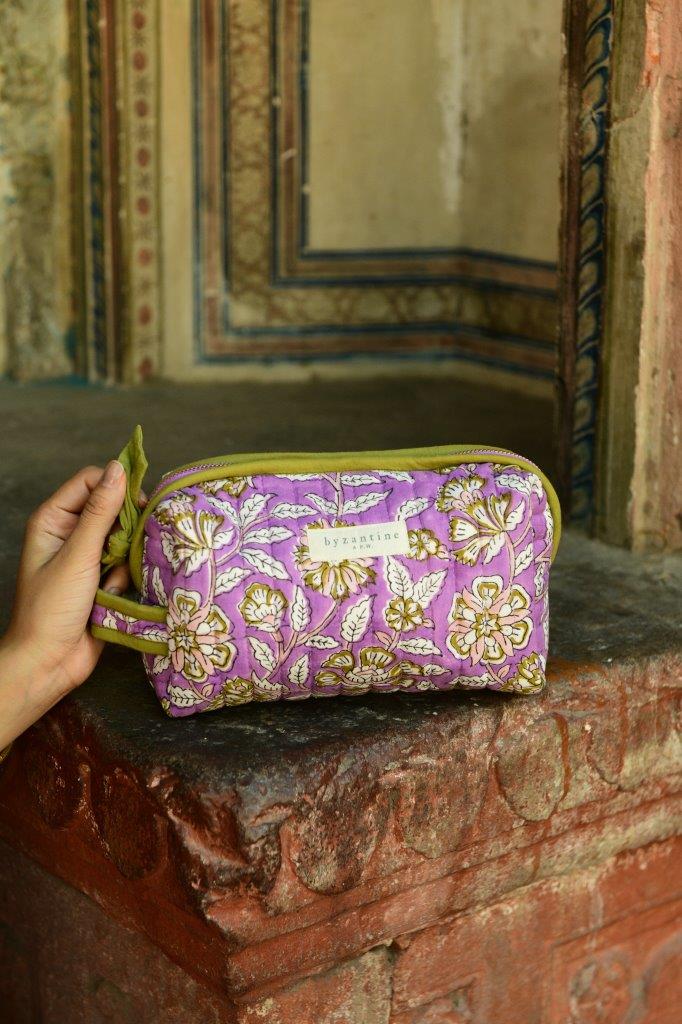 Petite trousse de toilette Carthage Lilas posée sur un muret ancien