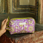 Petite trousse de toilette Carthage Lilas posée sur un muret ancien