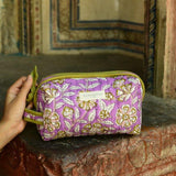 Petite trousse de toilette Carthage Lilas posée sur un muret ancien
