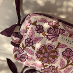 Gros plan sur le motif fleuri et le nœud de la trousse Carthage Prune