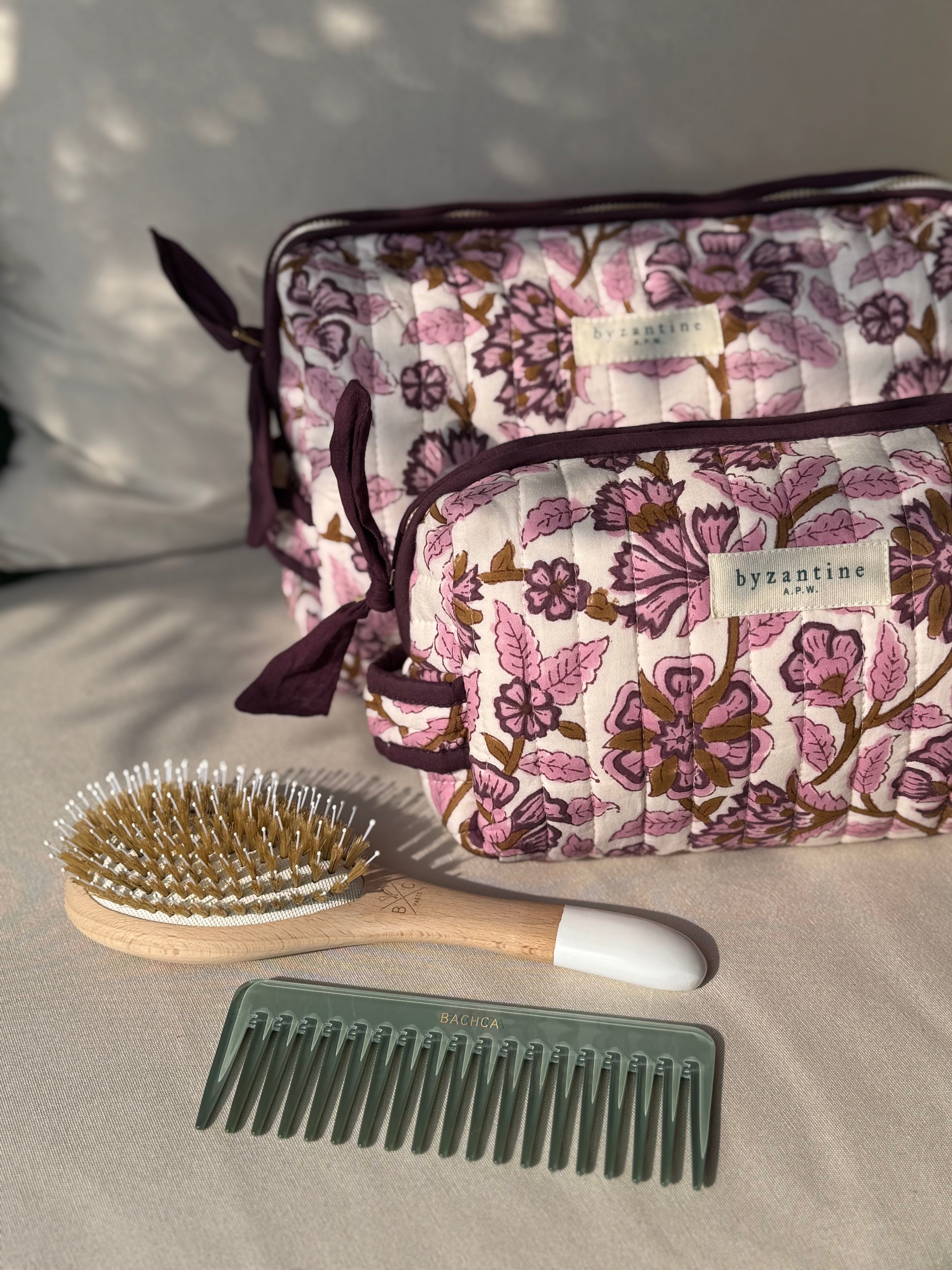 Duo de trousses de toilette Carthage Prune, brosse et peigne sur un canapé