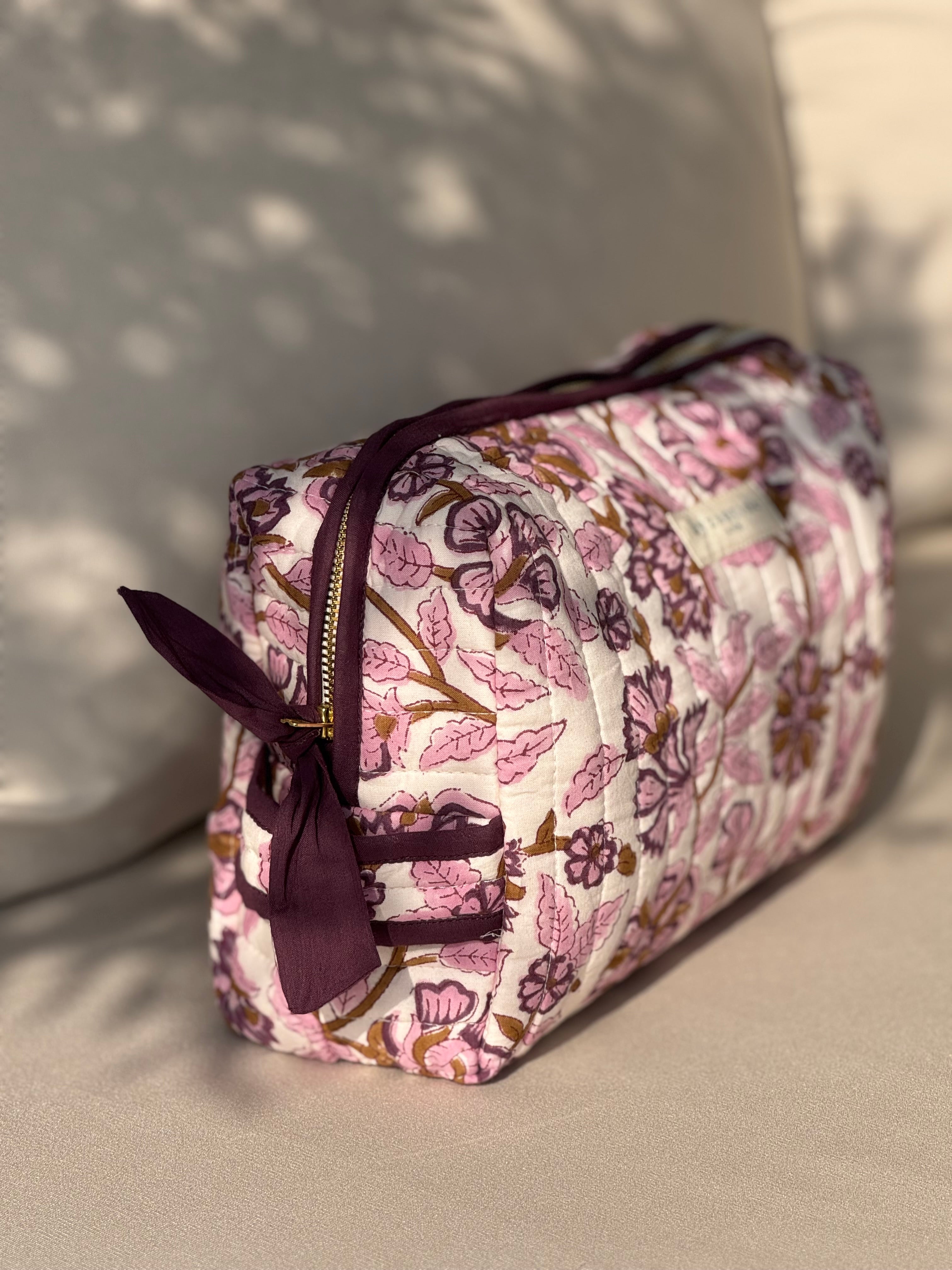 Trousse de toilette Carthage Prune à nœud, vue de côté sur un canapé