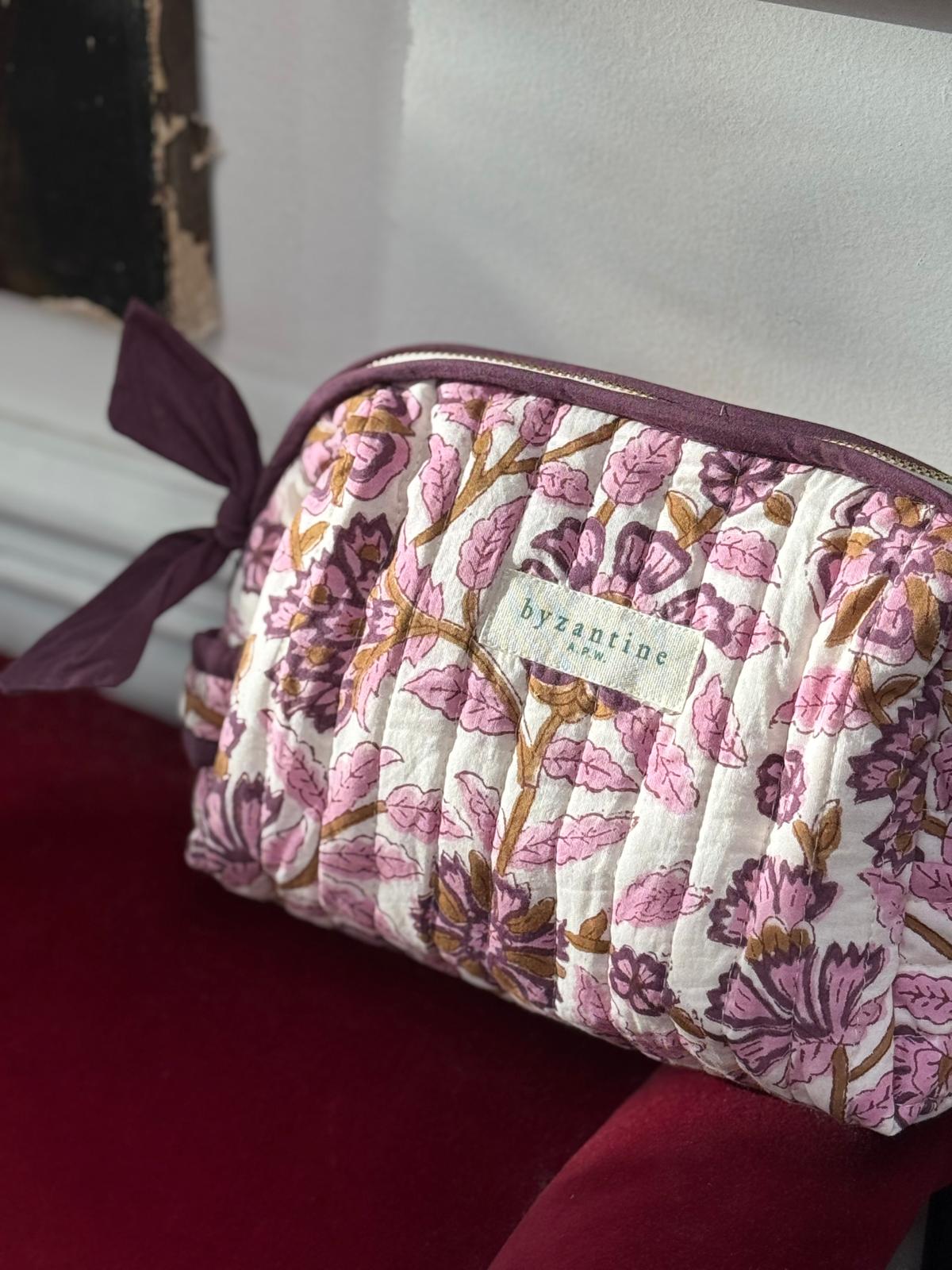 Trousse de toilette Carthage Prune posée sur un velours rouge