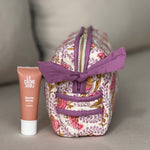 Petite trousse de toilette Éphèse Rose vue de côté, avec un tube de soin