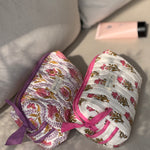Duo de trousses de toilette Éphèse Rose couchées sur un canapé