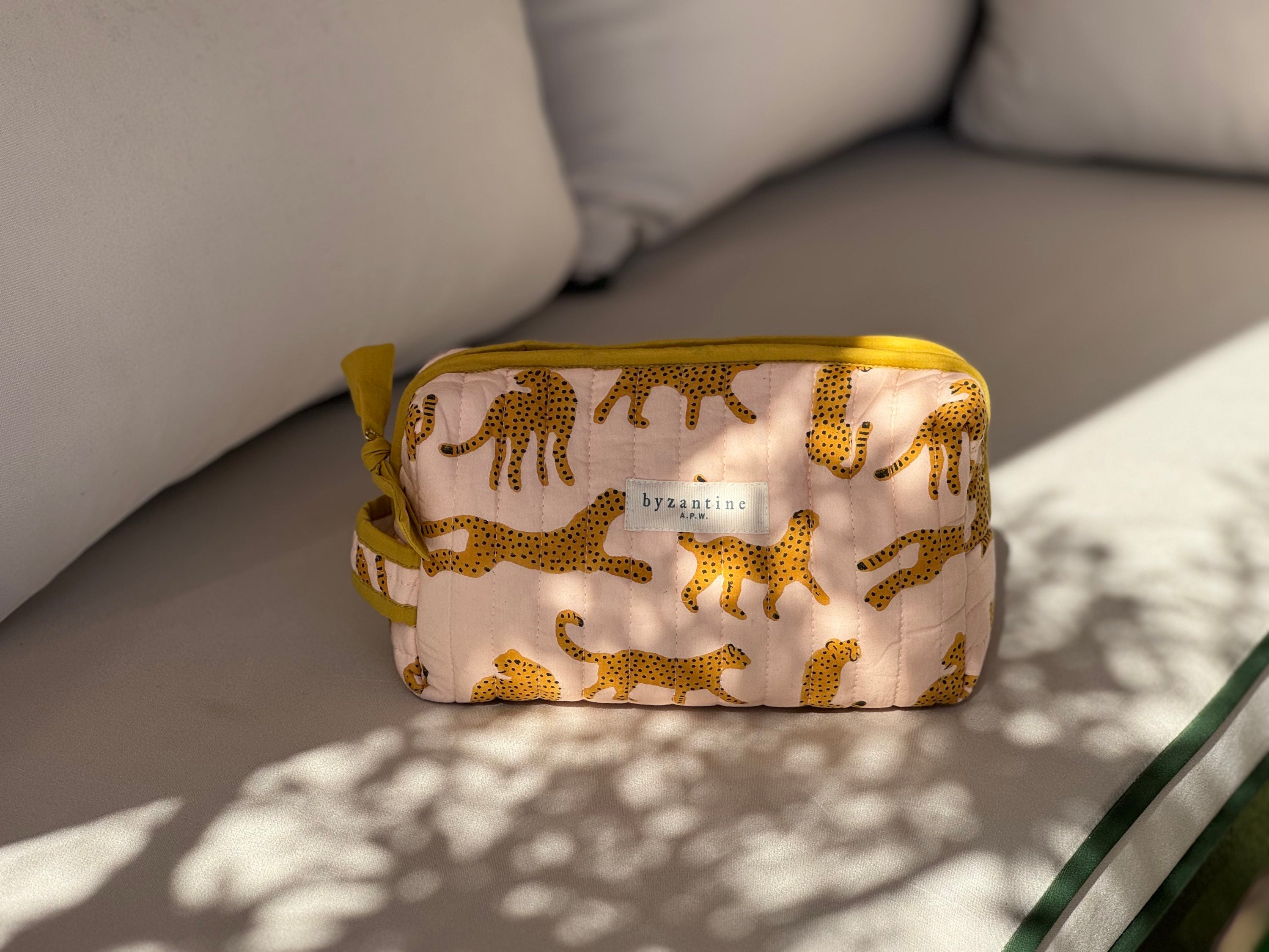 Petite trousse de toilette Fauve Rose de byzantine, guépards ocre sur fond rose, sur un banc