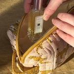 Main rangeant un flacon de parfum dans la petite trousse de toilette Fauve Rose