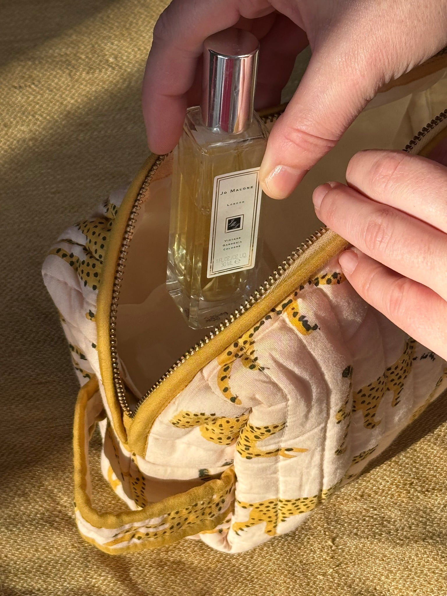 Main rangeant un flacon de parfum dans la petite trousse de toilette Fauve Rose