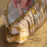 Main sortant un pinceau de la petite trousse de toilette Fauve Rose