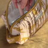 Main sortant un pinceau de la petite trousse de toilette Fauve Rose