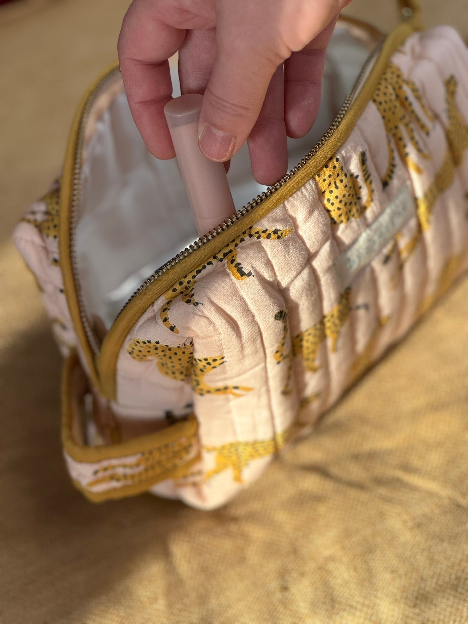 Main sortant un pinceau de la petite trousse de toilette Fauve Rose