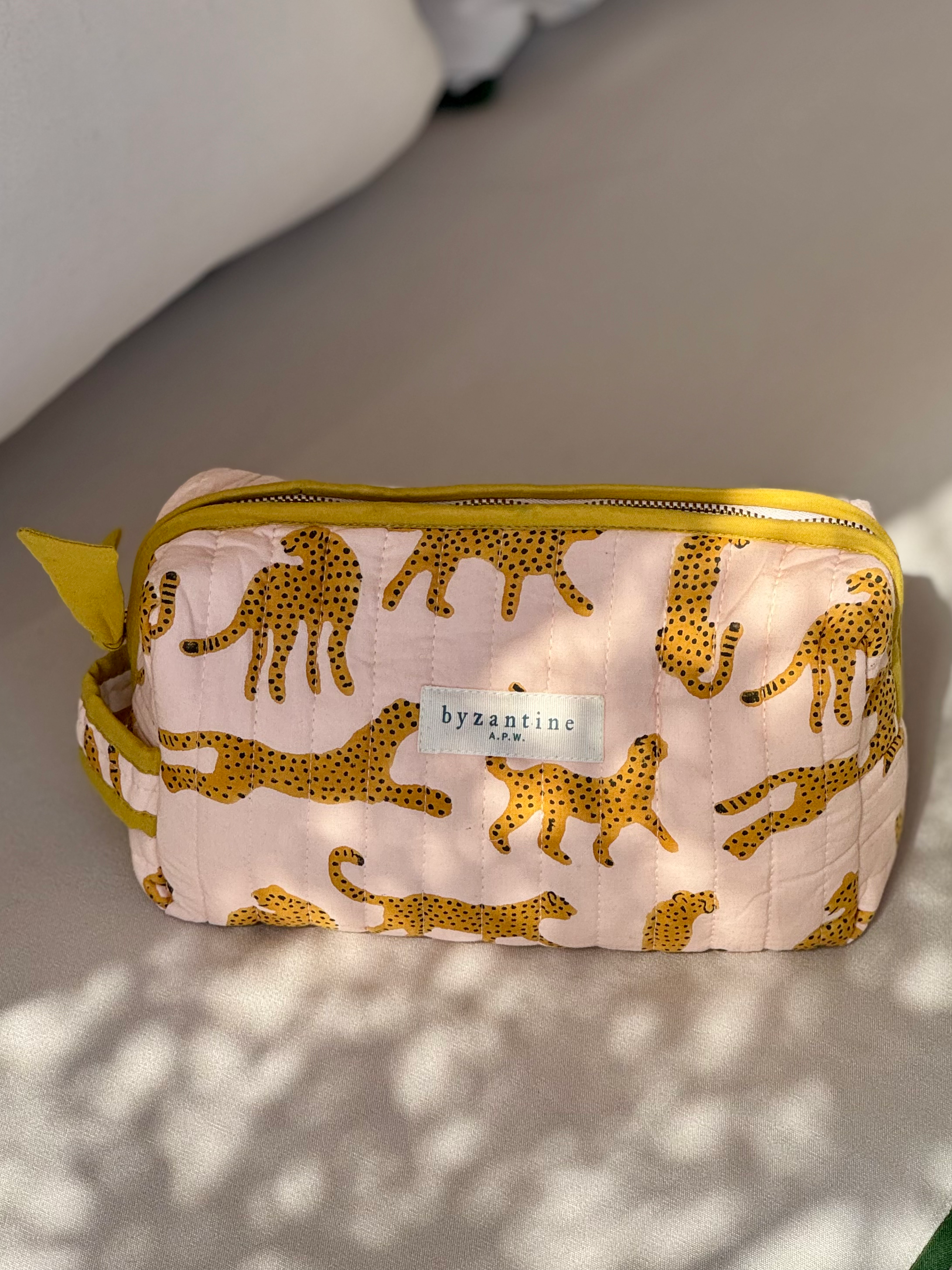 Petite trousse de toilette Fauve Rose posée sur un banc au soleil