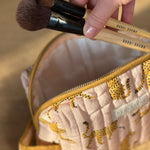 Pinceaux de maquillage sortant de la petite trousse de toilette Fauve Rose