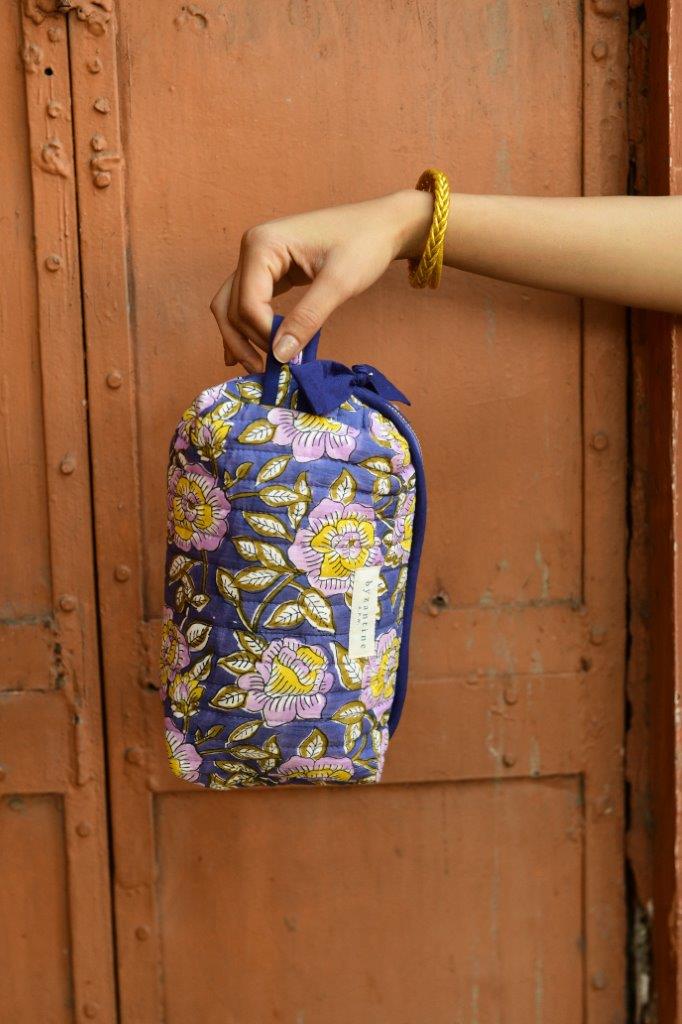 Petite trousse de toilette N°113 Bleu tenue à la main devant une porte