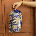 Petite trousse de toilette N°113 Bleu tenue à la main devant une porte