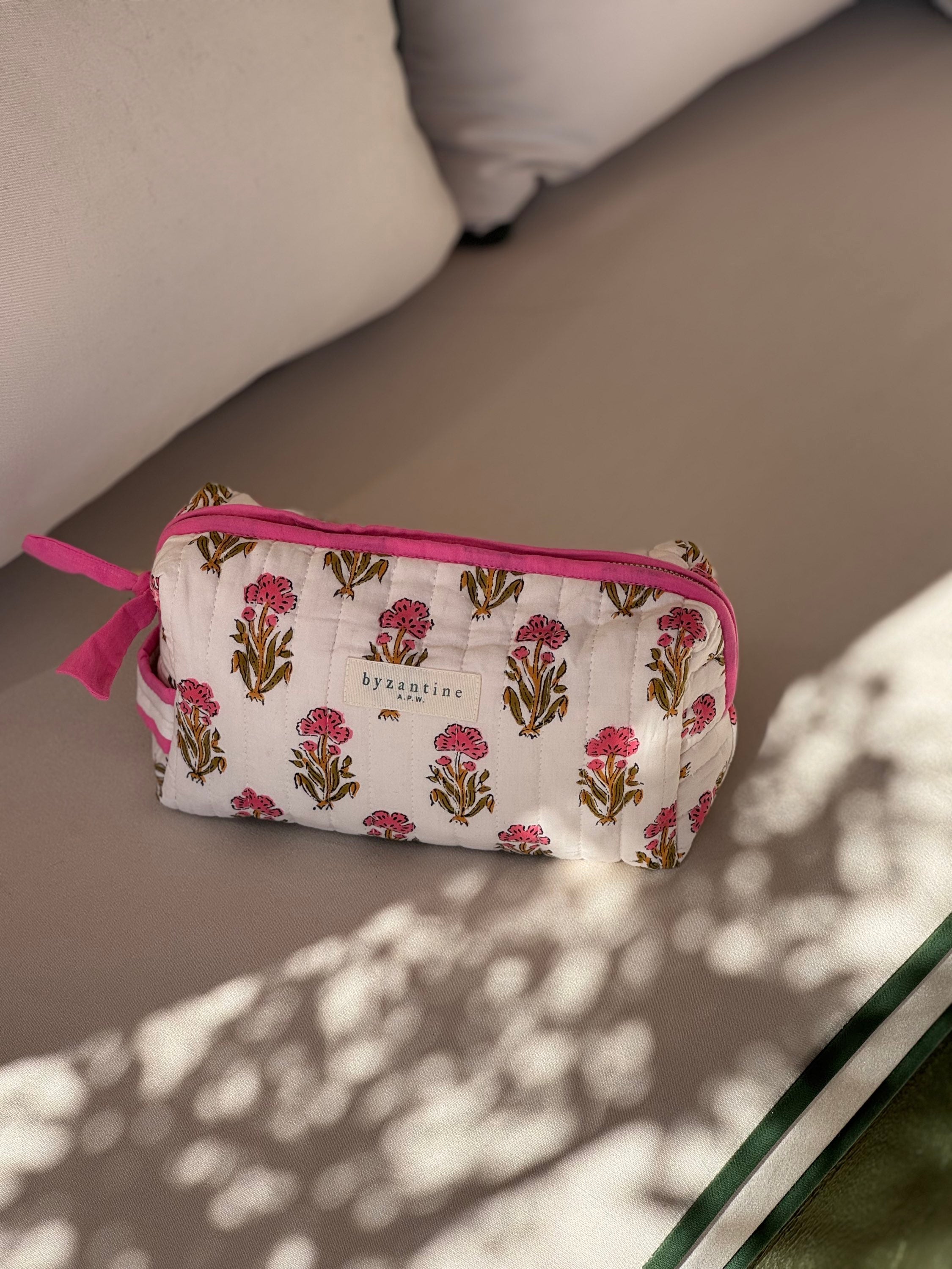 Petite trousse de toilette N°50 Rose fermée, posée sur un banc