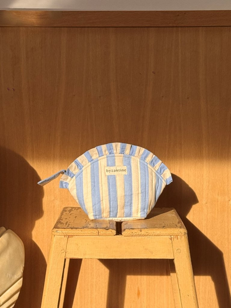 Petite trousse froufrou Pacha Bleu ciel posée sur un tabouret en bois