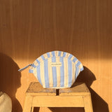 Petite trousse froufrou Pacha Bleu ciel posée sur un tabouret en bois