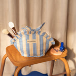 Petite trousse froufrou Pacha Bleu ciel nouée, avec pinceaux et vernis, sur un escabeau