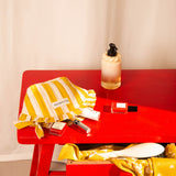 Petite trousse froufrou Pacha Passion sur une table rouge, avec un flacon et un vernis