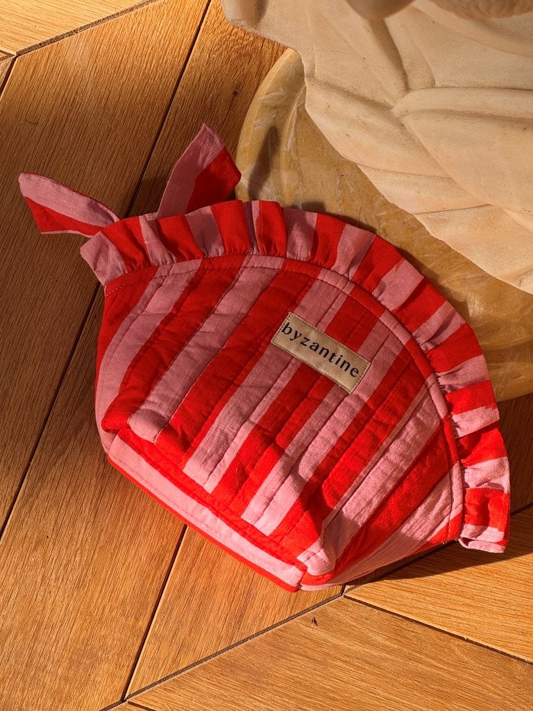 Petite trousse froufrou Pacha Tomato posée sur un parquet en bois