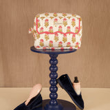 Petite trousse de toilette N°50 Rose sur un guéridon, mocassins en velours au sol