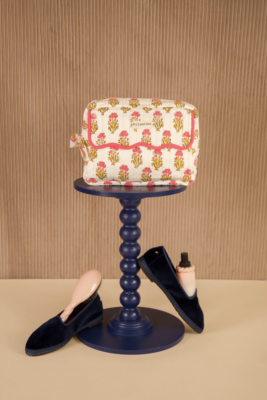 Petite trousse de toilette N°50 Rose sur un guéridon, mocassins en velours au sol
