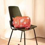 Petite trousse de toilette Antioche Tomato sur une chaise vert foncé, ballerines rouges