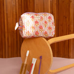 Petite trousse de toilette Éphèse Rose sur un tabouret renversé, mascaras au sol