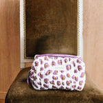 Petite trousse de toilette Léopard Écru et Violet de byzantine sur une chaise en velours