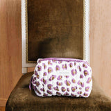Petite trousse de toilette Léopard Écru et Violet de byzantine sur une chaise en velours
