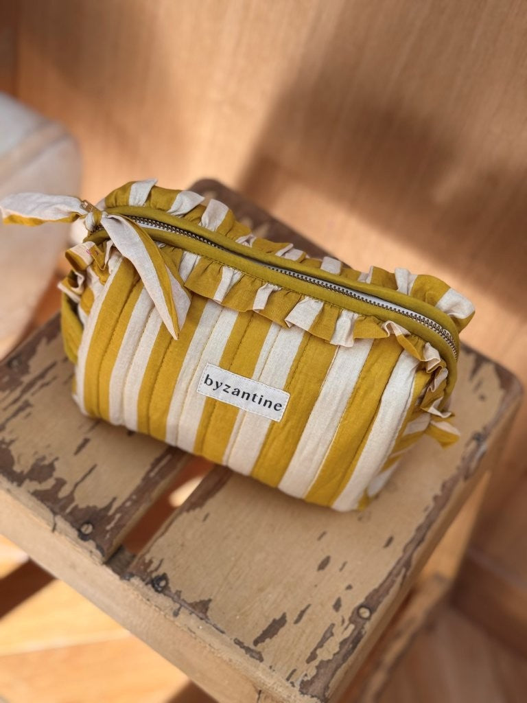 Petite trousse à volants Pacha Passion à nœud, posée sur un tabouret en bois