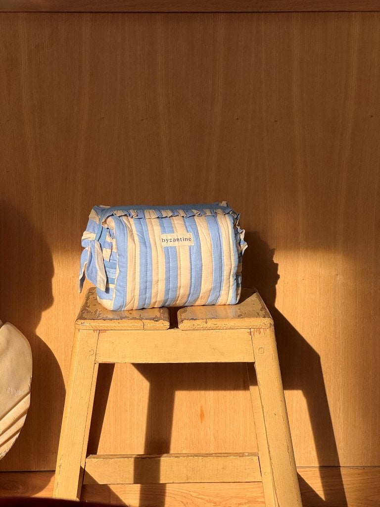Petite trousse à volants Pacha Bleu ciel posée sur un tabouret en bois