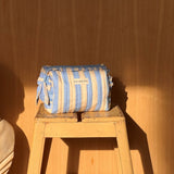 Petite trousse à volants Pacha Bleu ciel posée sur un tabouret en bois