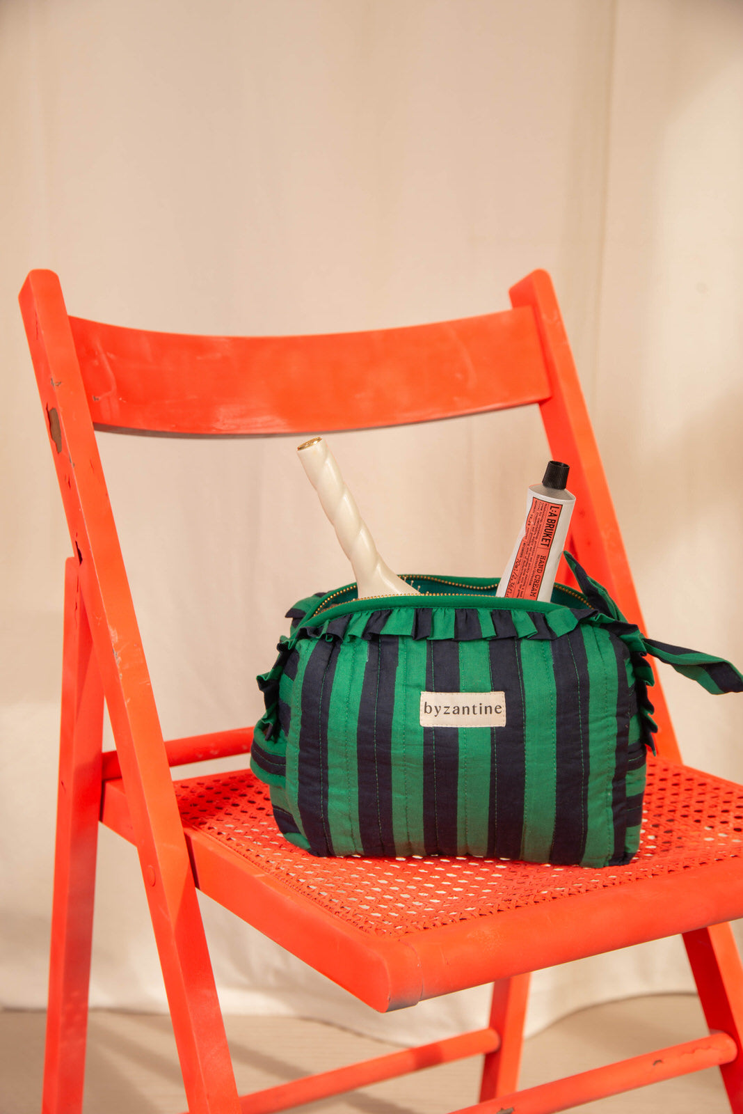 Petite trousse volants Pacha Menthe avec pinceaux, posée sur une chaise orange