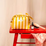 Petite trousse volants Pacha Passion nouée sur une table rouge, avec une brosse