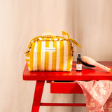 Petite trousse volants Pacha Passion nouée sur une table rouge, avec une brosse