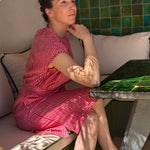 Robe Charlotte Fraise portée, femme assise accoudée à une table carrelée