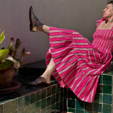 Robe Froufrou Fluo Pink portée, femme assise jambe levée sur un banc carrelé