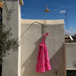 Robe Froufrou Fluo Pink suspendue à une douche extérieure sur un toit
