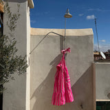 Robe Froufrou Fluo Pink suspendue à une douche extérieure sur un toit