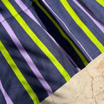 Gros plan sur les rayures marine, lilas et vert fluo de la robe Liberty