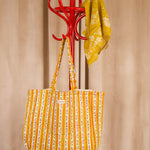 Sac cabas Flora Passion de Byzantine, rayures fleuries jaunes, suspendu à un porte-manteau rouge