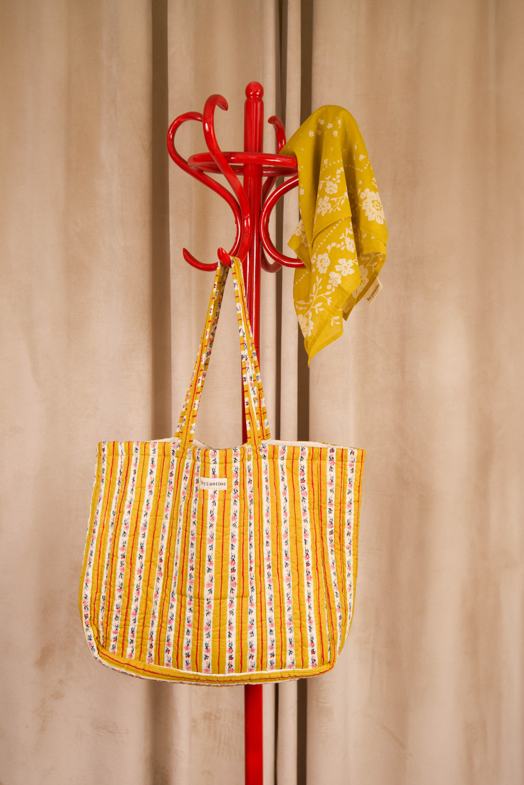Sac cabas Flora Passion de Byzantine, rayures fleuries jaunes, suspendu à un porte-manteau rouge
